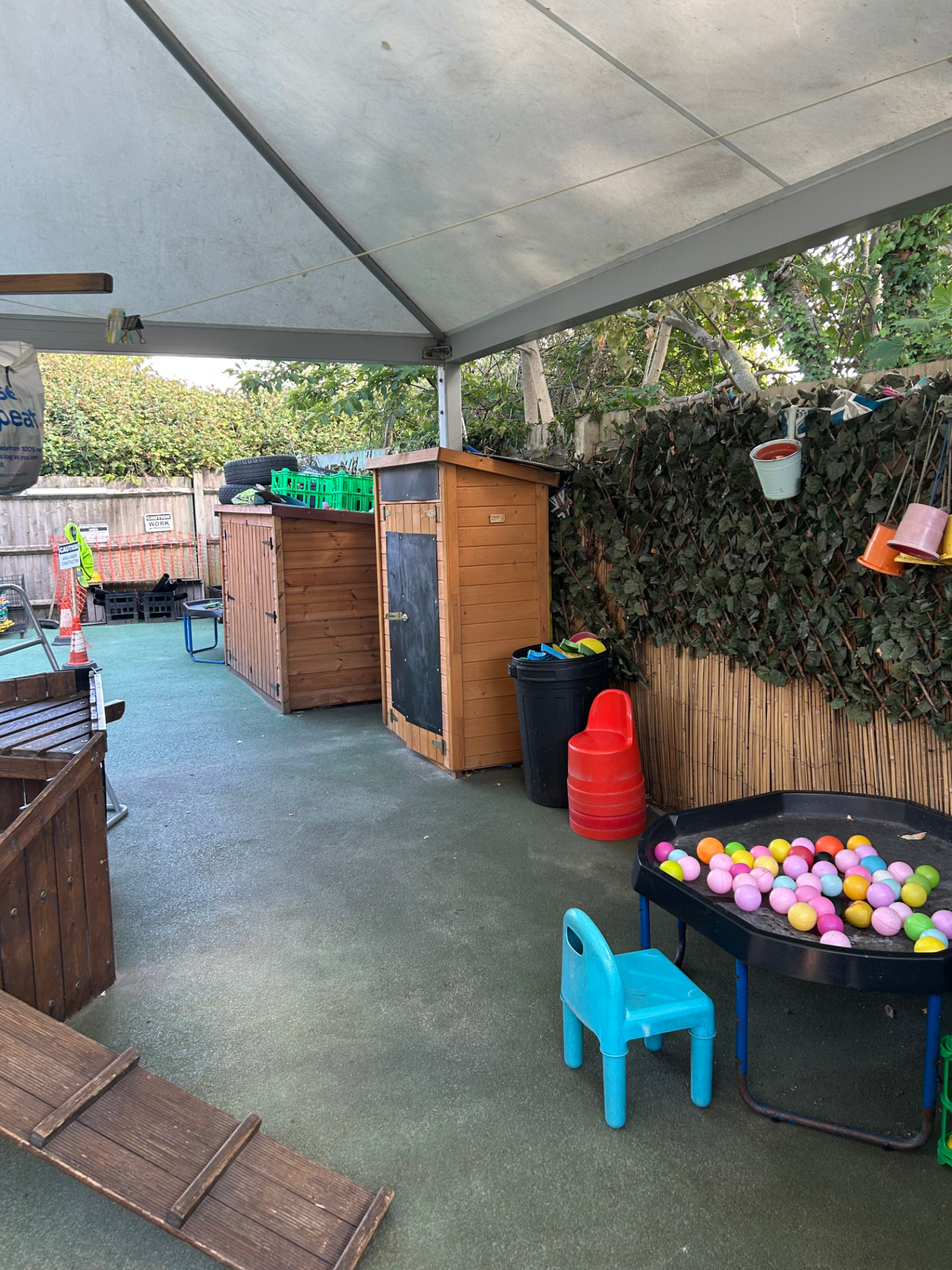 Covered outdoor play area with a ball pit, storage and sensory toys