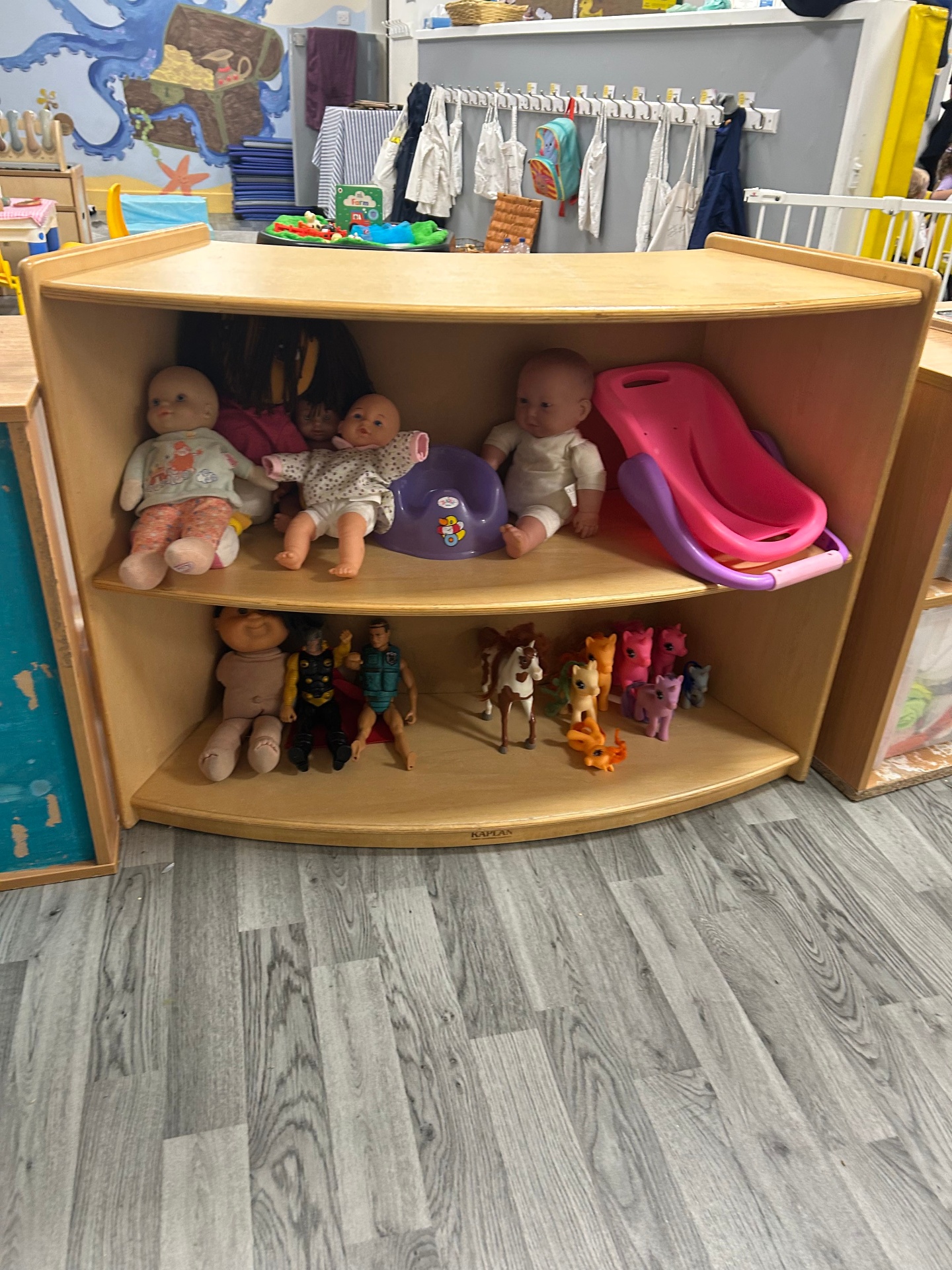 Curved low-level shelf with dolls and accessible play resources