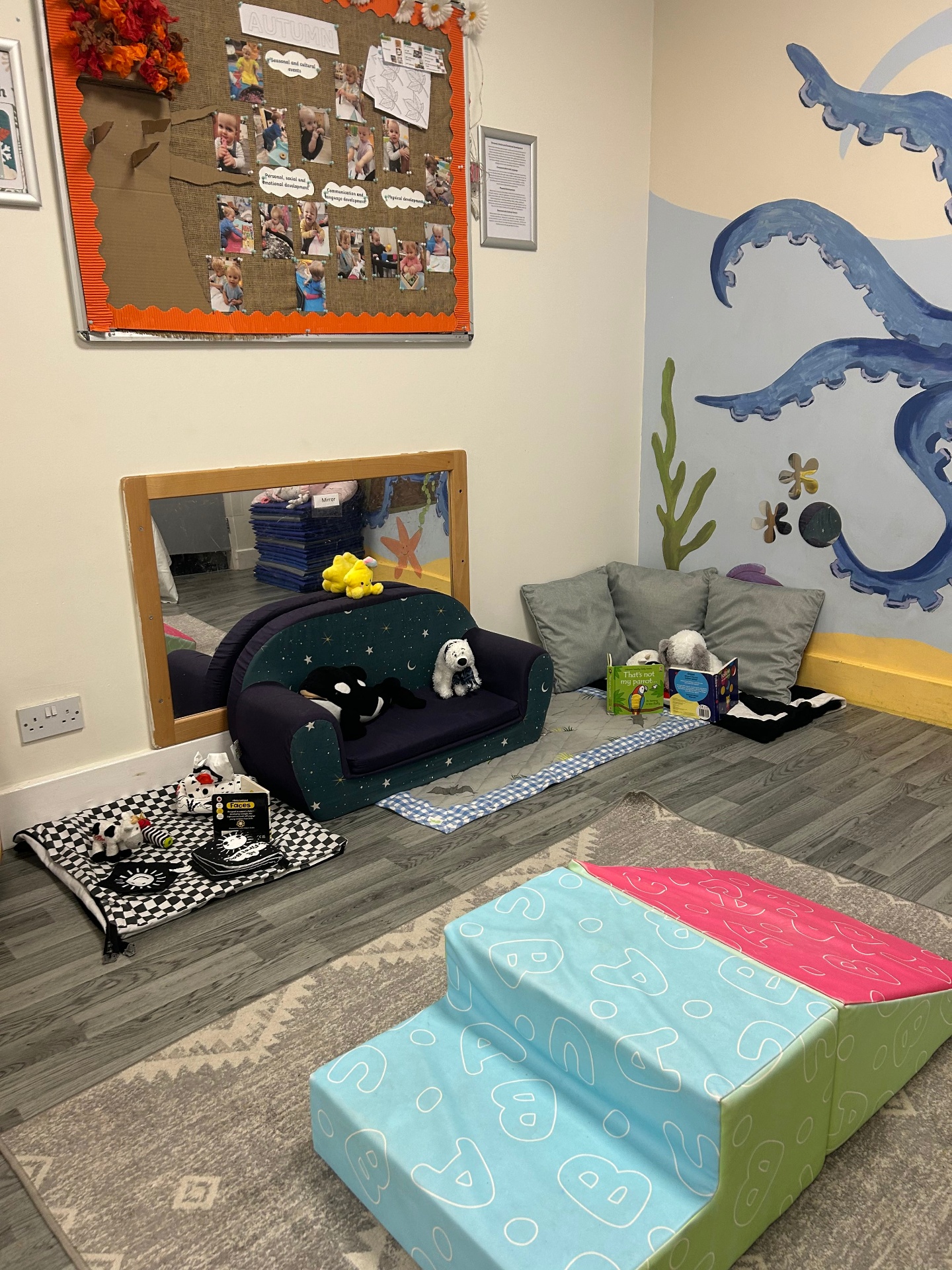 Cosy baby room corner with a small sofa and low-level mirrors