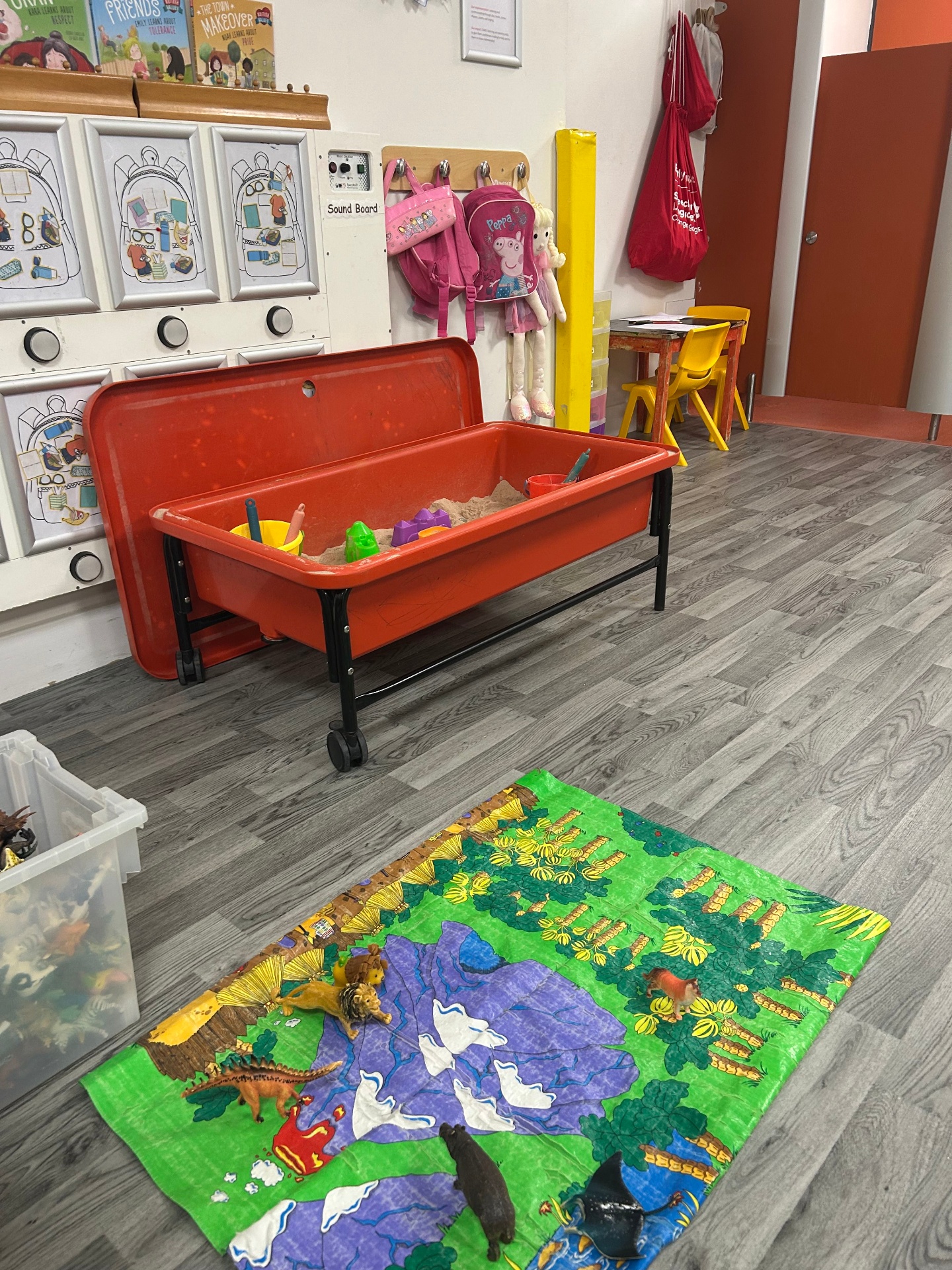 Sensory play tray beside a colourful animal rug