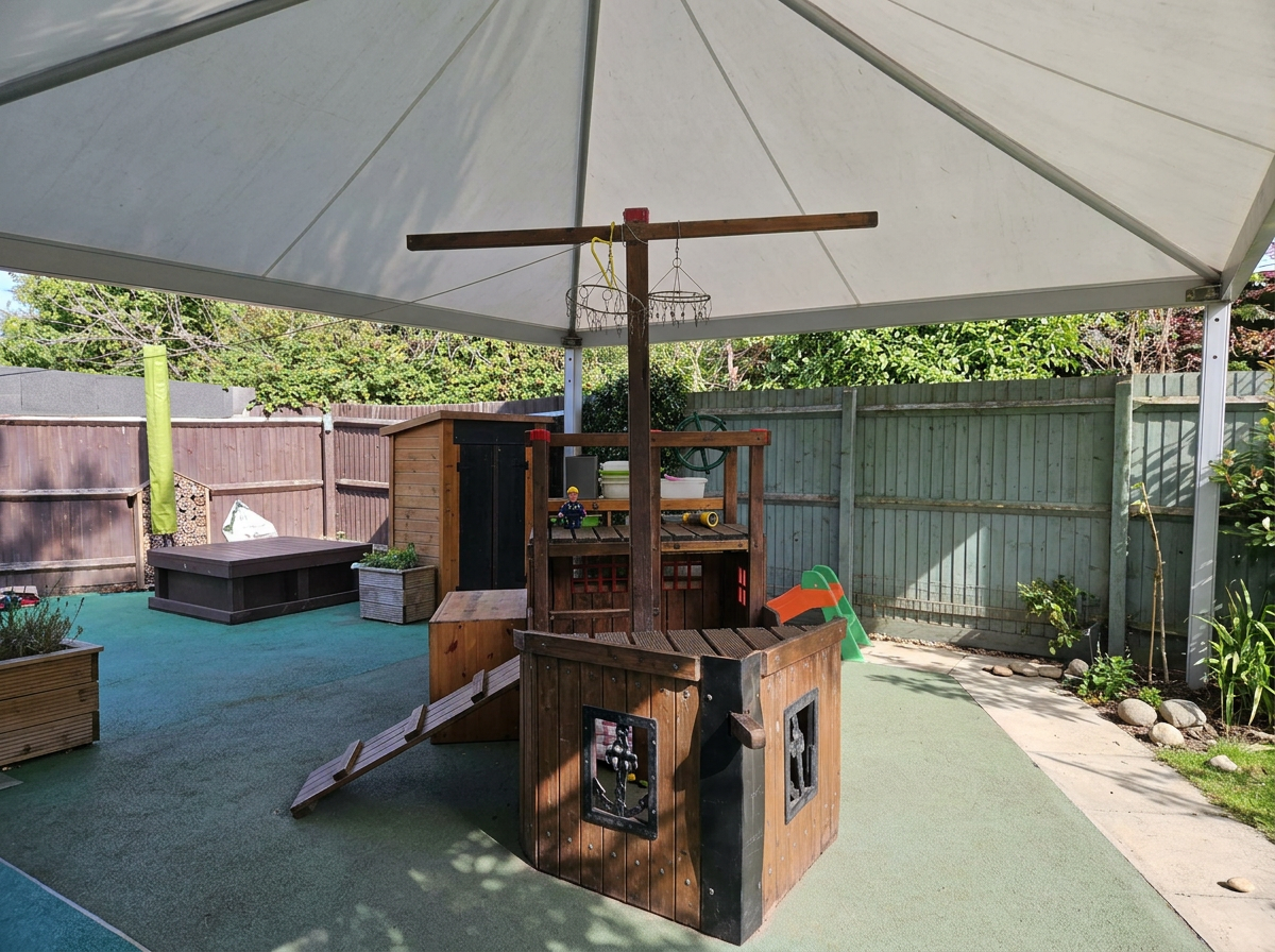 Wooden pirate ship play structure under the garden canopy