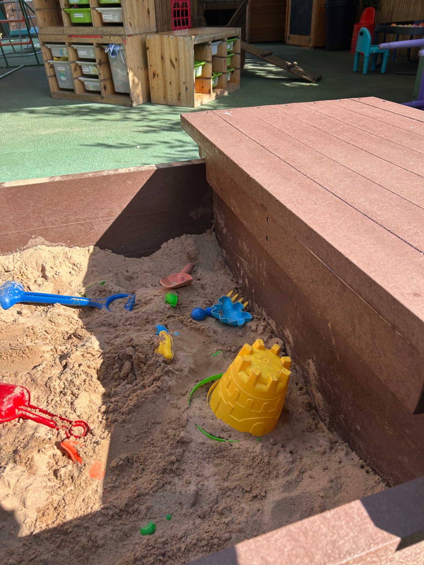 Large wooden sandpit prepared with outdoor toys